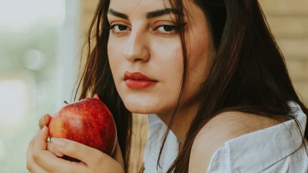 a woman holding an apple in her right hand